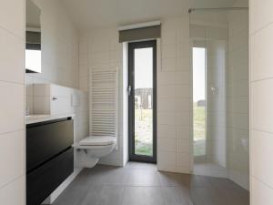 a white bathroom with a toilet and a window at Holiday Home Wissenkerke near Nature Reserve in Wissenkerke +32 photos