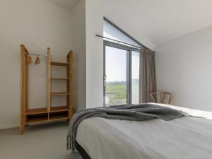 a white bedroom with a bed and a window at Holiday Home Wissenkerke near Nature Reserve in Wissenkerke
