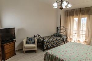 a bedroom with a bed and a tv and a chair at Casa vacanza La Seggiara in San Giovanni Incarico