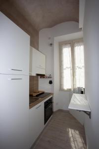 a small kitchen with white cabinets and a window at La finestra sul pincio in Civitavecchia +1 photo