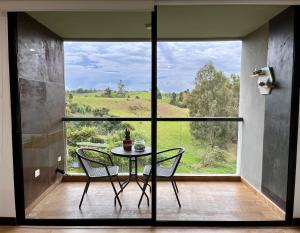 uma mesa e cadeiras num quarto com uma grande janela em Hotel Rioverde em Rionegro
