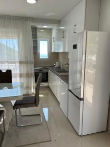 a kitchen with a refrigerator and a table with a chair at Apartmani Planinska Idila in Bar