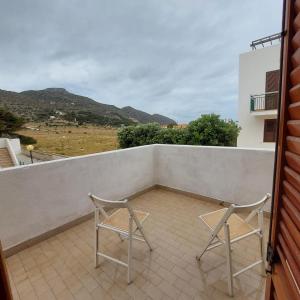 twee stoelen op een balkon met bergen op de achtergrond bij Casa Paco in Favignana +3 foto's