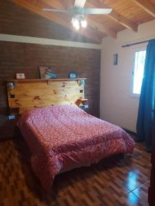 a bedroom with a red bed with a wooden headboard at somos "EL FIN DEL AFAN" 2, casa con vistas a las sierras in Potrero de los Funes