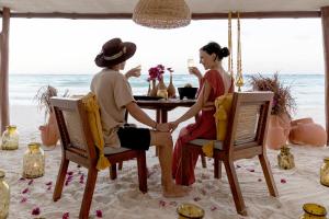 um homem e uma mulher sentados numa mesa na praia em La Zebra Boutique Hotel em Tulum