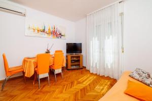 a living room with a table and chairs and a television at Apartments and Room Petar in Banjol