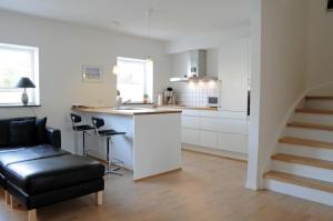 a kitchen with white cabinets and a black leather chair at Skagen Apartment in Skagen
