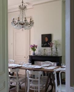 a dining room with a table with chairs and a chandelier at Les séquoias géants in Saint-Martin-aux-Arbres