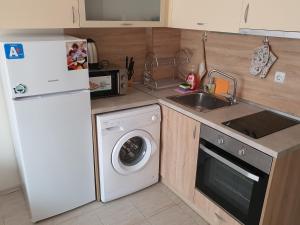 uma cozinha com um frigorífico branco e uma máquina de lavar roupa em Таня 10 em Pomorie