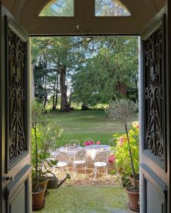 eine offene Tür zu einer Terrasse mit einem Tisch und Stühlen in der Unterkunft Les séquoias géants in Saint-Martin-aux-Arbres