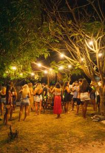 a group of people standing under a tree at night at Padang Hostel in Pipa