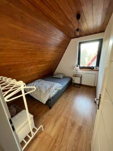een slaapkamer met een bed in een kamer met een houten plafond bij Dom na Gazownikow12 in Brenna