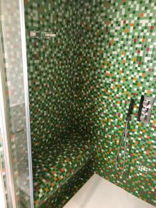 La salle de bains est pourvue d'une douche avec du carrelage vert et coloré. dans l'établissement COCCIU D’AMURI, à Castellammare del Golfo