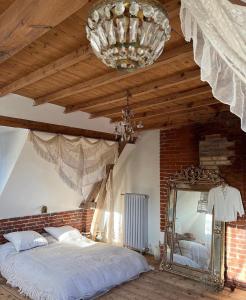 Schlafzimmer mit einem Bett, einem Spiegel und einem Kronleuchter in der Unterkunft Les séquoias géants in Saint-Martin-aux-Arbres
