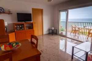 a living room with a television and a balcony with the ocean at AP Over the Sea in Arenales del Sol