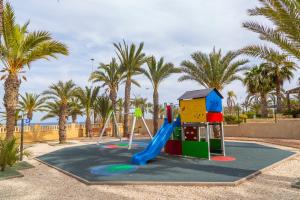 a playground in a park with palm trees and a slide at AP Over the Sea in Arenales del Sol