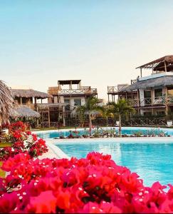 a swimming pool with pink flowers in front of a resort at Casa Tangerina BG, seu Bangalô frente mar em Barra Grande-PI in Barra Grande