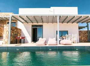 a house with pink pillows sitting next to the water at Summer Villa Barbara ,private pool in Mikonos