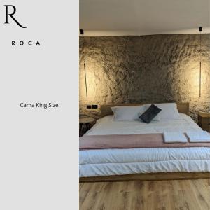 a bedroom with a white bed with a brick wall at Roca Lodge in Quito