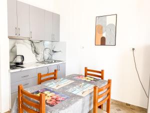 una cucina con tavolo e sedie e una cucina con armadietti bianchi di LunaSol seaside Apartments a Durrës