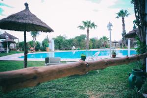 une clôture en bois avec un parasol et une piscine dans l'établissement Hotel Le Khalife, à Hammamet