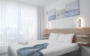 a bedroom with a large white bed and a window at סוויטה עם נוף וצמודה לים במתחם SeaSide היוקרתי עם בריכה - By SEAELO EILAT in Eilat +7 photos