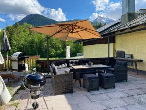 ビショフスヴィーゼンにあるC4S COME4STAY - Alpenblick Watzmann-Kehlstein - TOP Lage im Berchtesgadener Land I bis zu 10 Personen I große Terrasse mit Blick auf die Berge I Smart TV I Billiard I WLAN I kostenloser Parkplatzのテーブルと椅子と傘のあるパティオ
