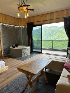 a room with a bath tub and a table and a large window at Primland Suit in Çamlıhemşin