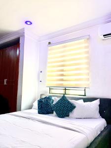 sypialnia z łóżkiem z niebieskimi poduszkami i oknem w obiekcie Vintage Classic Suites w mieście Lagos