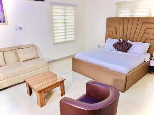 a bedroom with a bed and a couch and a chair at Vintage Classic Suites in Lagos
