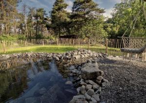 a pond in a yard with rocks and a fence at WOODMOOD Caravan Experience in Leuk
