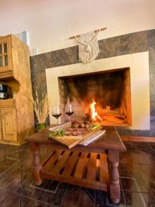 a fireplace with a table with food and wine glasses at El Solar Casas de Campo 3 in Valle Grande