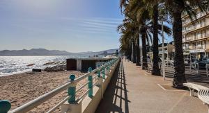 un trottoir à côté d'une plage bordée de palmiers et d'un bâtiment dans l'établissement Superbe appartement à Cannes / 3 chambres, à Cannes