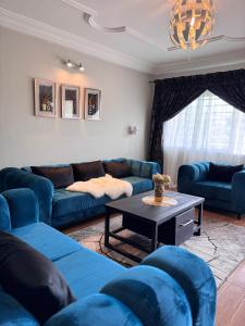 una sala de estar con sofás azules y una mesa. en Akhard Haus en Buea