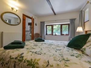 ein Schlafzimmer mit einem großen Bett mit grünen Kissen darauf in der Unterkunft Buster Barn in Sampford Spiney