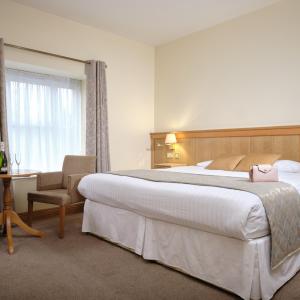 a hotel room with a large bed and a chair at Mahon's Hotel in Irvinestown