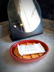 un cuenco rojo con una caja de comida delante de un espejo en Hostal Cristina, en Chipiona