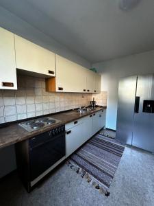 eine Küche mit weißen Schränken, einer Spüle und einem Kühlschrank in der Unterkunft Hansestraße in Lübeck