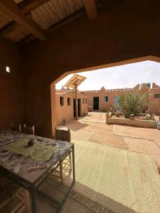 a patio with a table and a large window at Auberge Sahara Iriki & Désert Tours in Foum Zguid