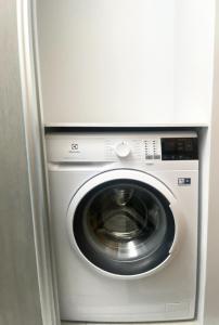 uma máquina de lavar e secar roupa num quarto branco em Jaukus butas Jonavoje em Jonava