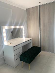 a bathroom with a vanity with a mirror and a green ottoman at Jaukus butas Jonavoje in Jonava
