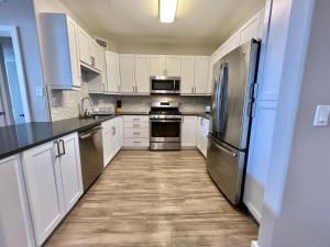 una cocina con armarios blancos y electrodomésticos de acero inoxidable en Spacious 2 Bedroom 2 Bathroom In Gated Community, en Los Ángeles