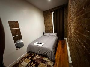 a bed in a room with a brick wall at Cozy Townhouse in Harlem in New York