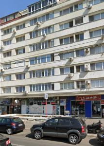 un grand bâtiment avec des voitures garées devant lui dans l'établissement Modern & Cozy 2 rooms apartment, à Bucarest