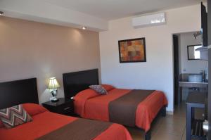 una camera d'albergo con due letti con lenzuola rosse di Hotel Los Valles a Creel