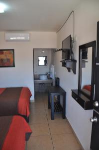 a room with a bed and a desk and a television at Hotel Los Valles in Creel