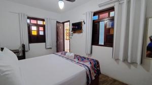 1 dormitorio con 1 cama en una habitación con ventanas en Pousada Du’Forte en Praia do Forte