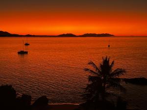 einen Sonnenuntergang über einem Wasserkörper mit Booten darin in der Unterkunft Coral Cove Apartments in Bowen