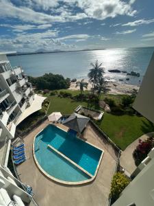 an aerial view of a swimming pool and the ocean at Coral Cove Apartments - Absolute Beachfront Resort Bowen in Bowen
