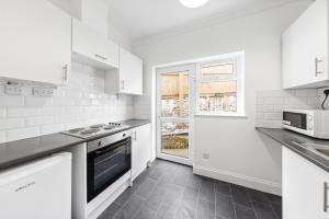 a white kitchen with white appliances and a window at Chic Flat in Medway Comfort & Style in Chatham